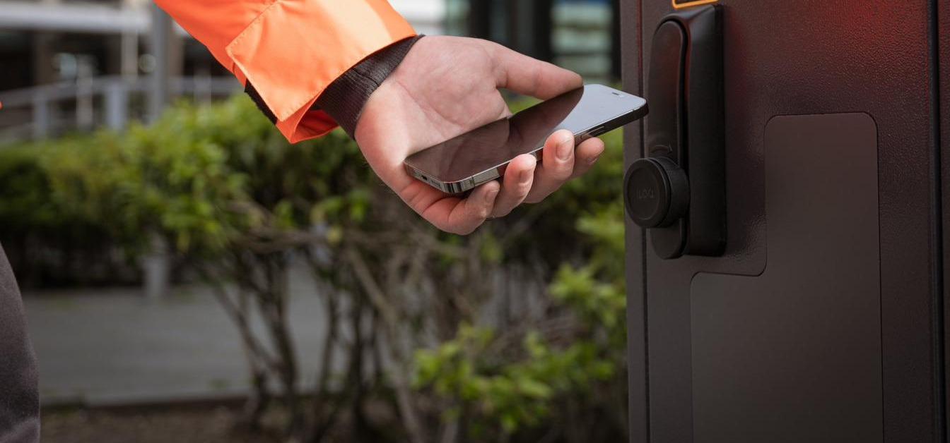 A field worker opening a technical cabinet with a phone