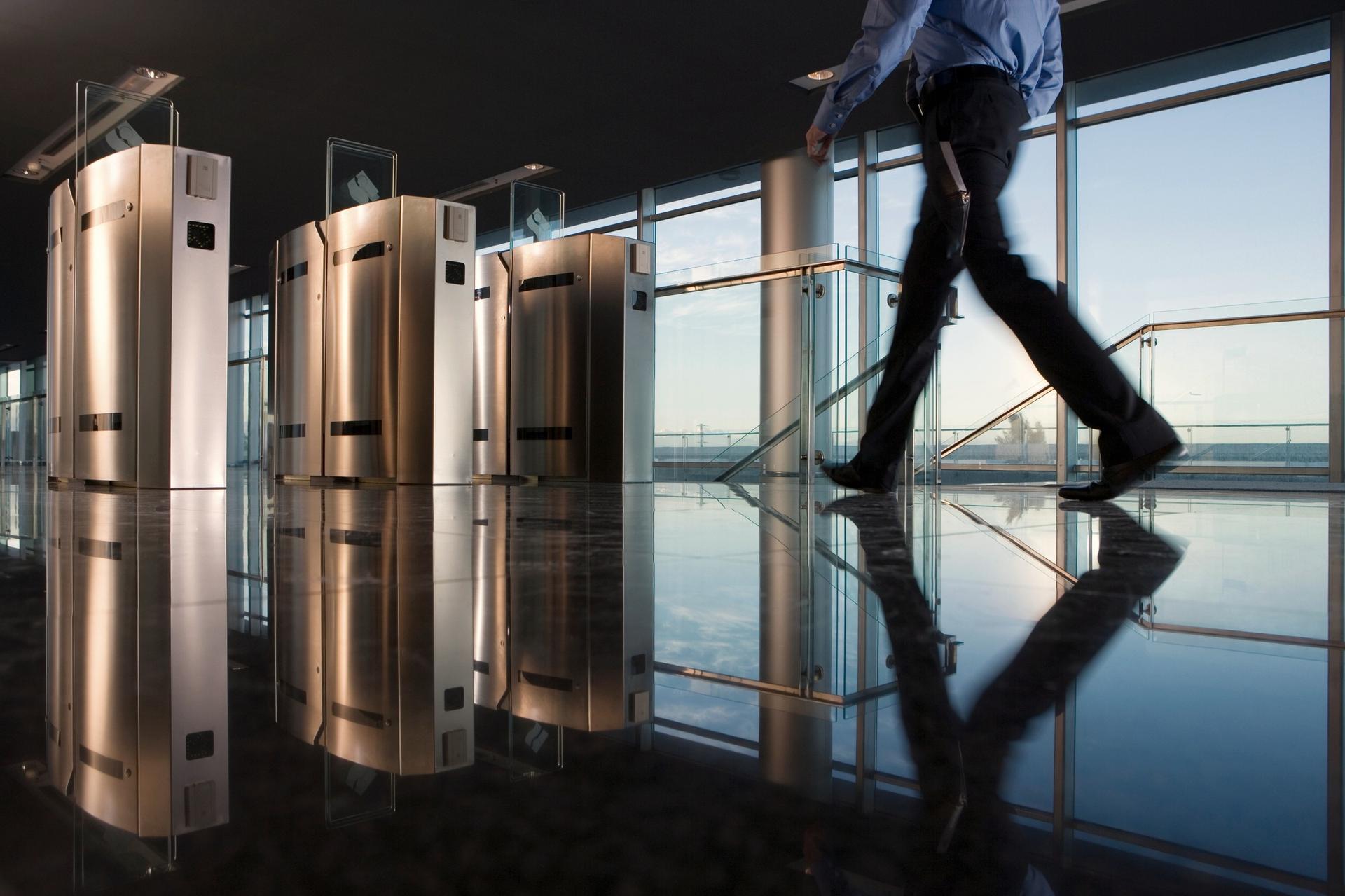A person walking through speed gates in a glass entrance hall