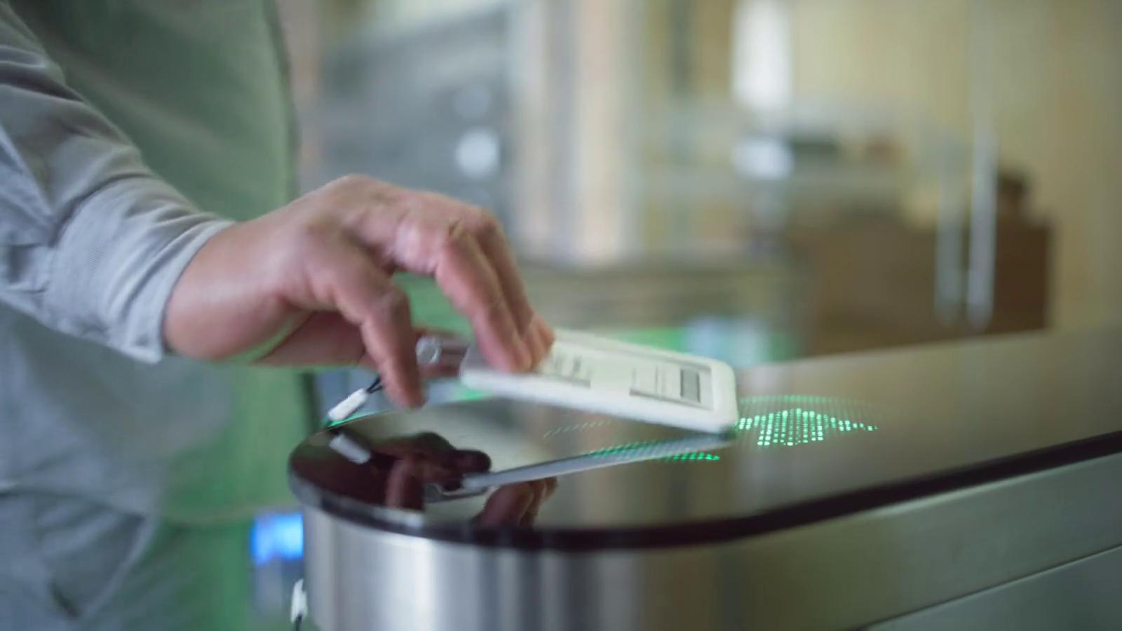 A badge held to the reader of an office turnstile, which lights up green
