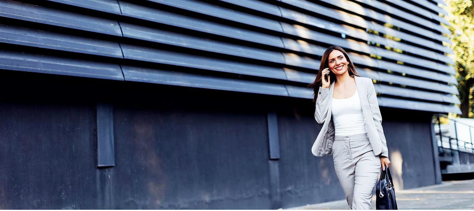 A woman on the phone walking past a modern building