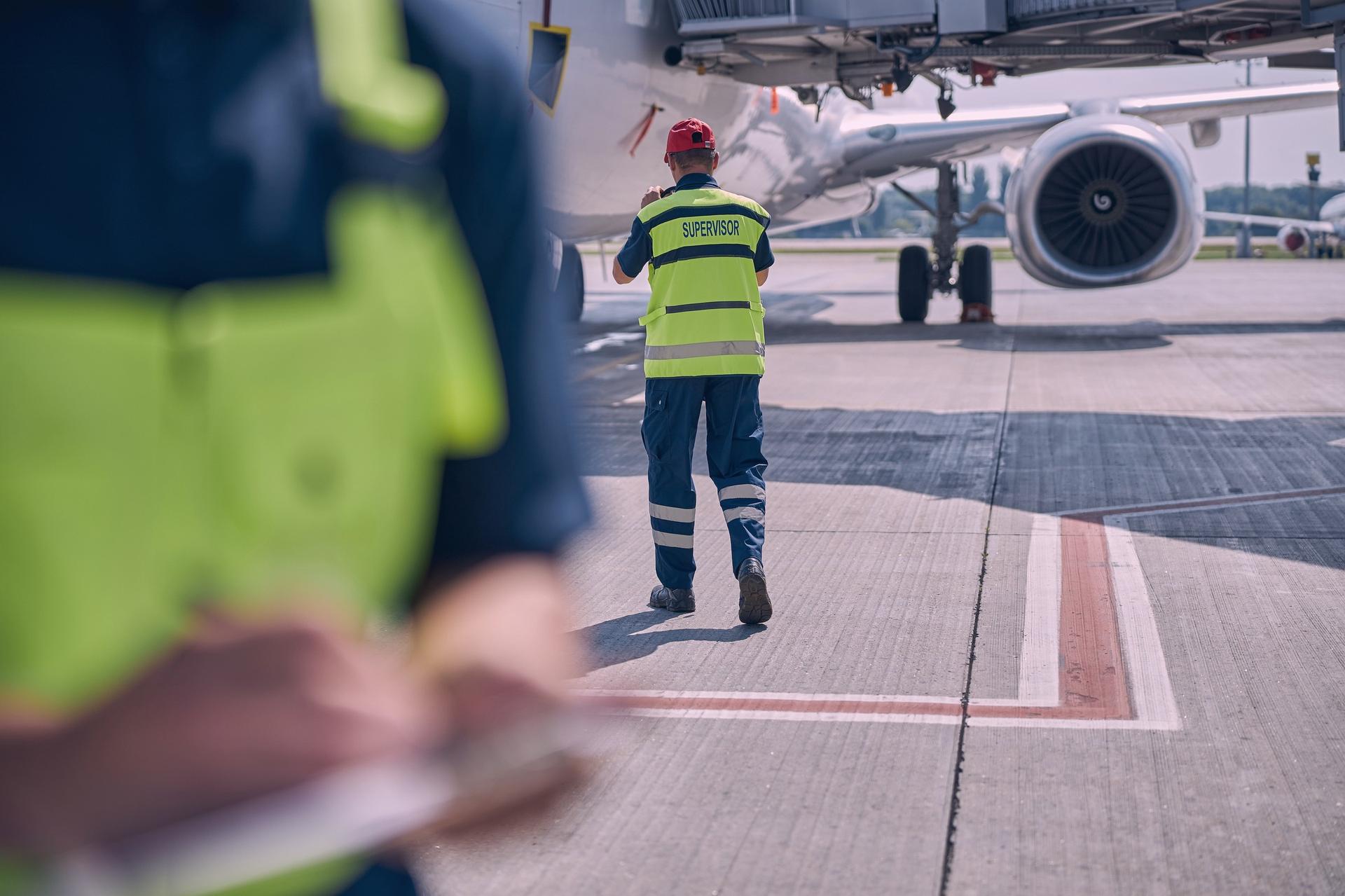 A ground handler walking towards an aircraft on the apron